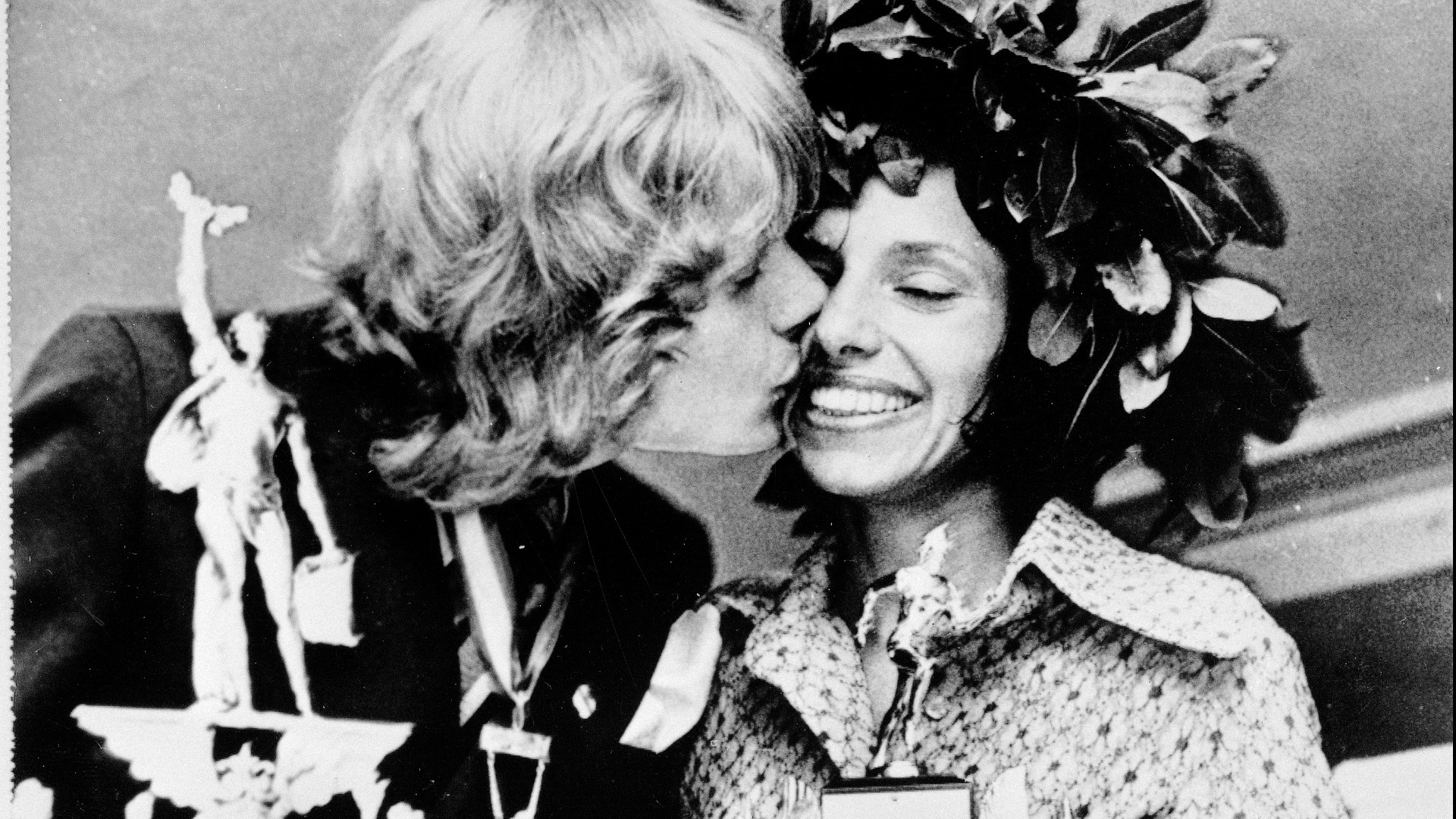 Olavi Suomalainen of Finland, winner of the men's division of the 1972 Boston Marathon, kisses Nina Kuscsik of the United States, winner of the women's division, at the trophy presentation.