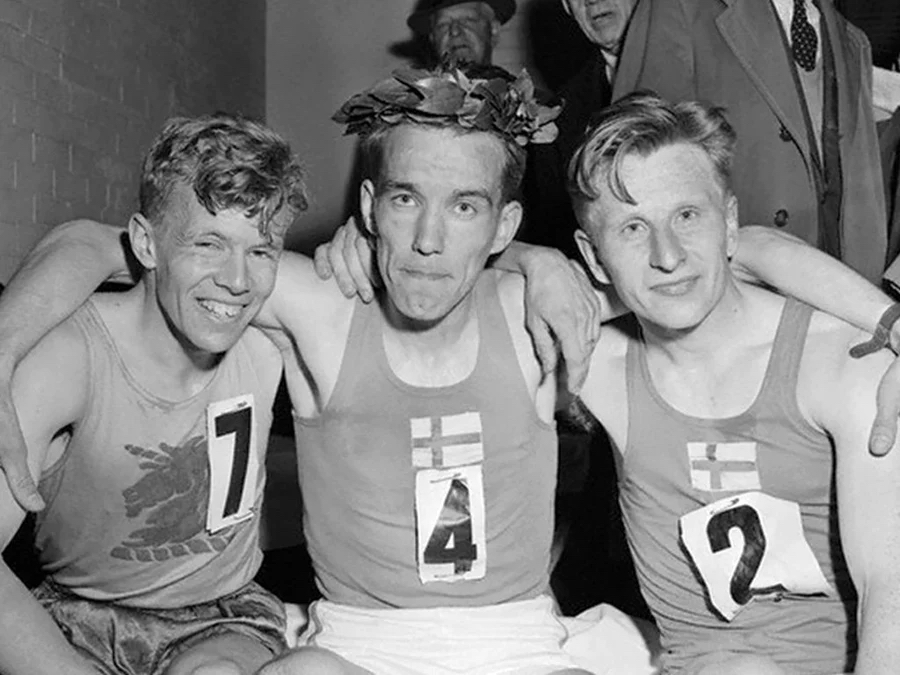 Three former Finnish distance runners smiling, with their arms around eachother.