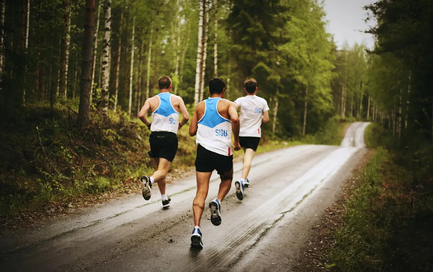 Three people running through a forest in Finland.