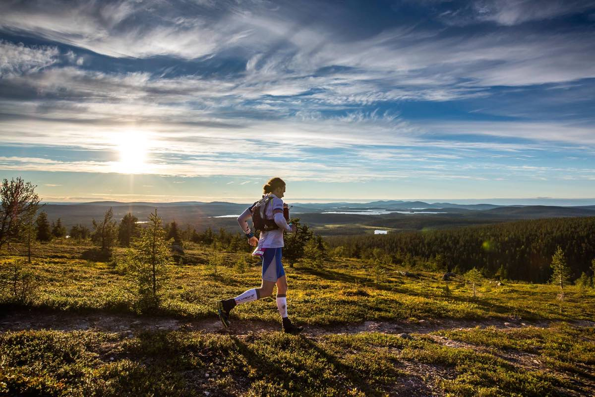 A person running along a trail with a backpack on.