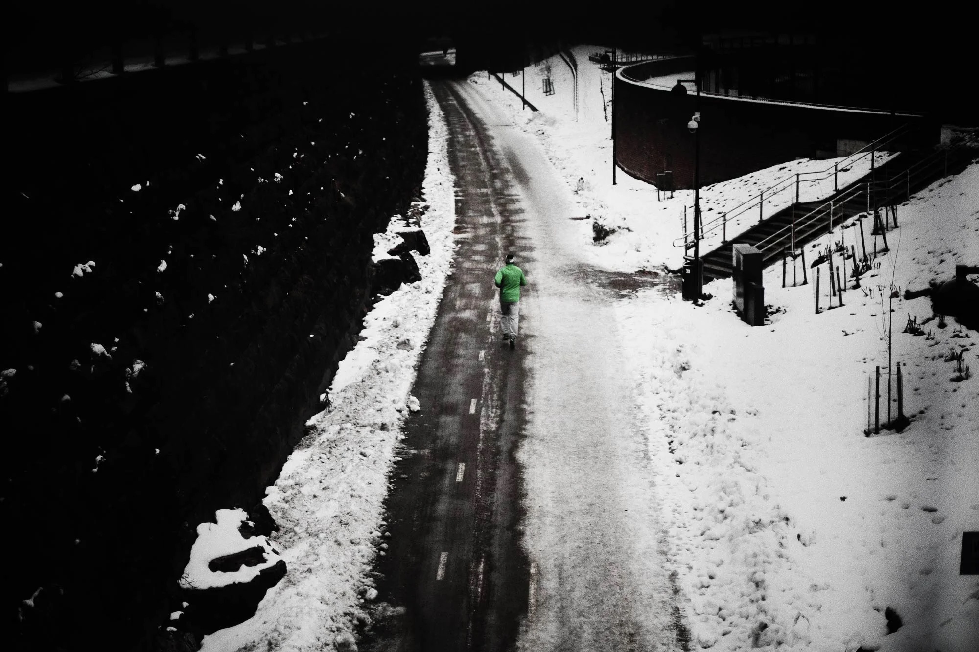 A person running along a road right next to a frozen lake, viewed from above.